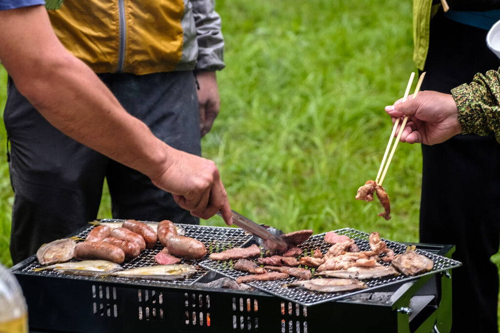 BBQ会場で料理を用意する担当者と食事を楽しむ参加者